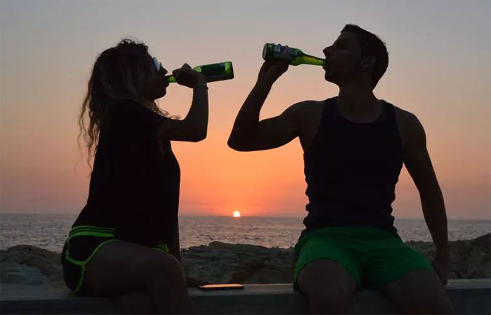 太阳落下时在海边喝酒的一对情侣