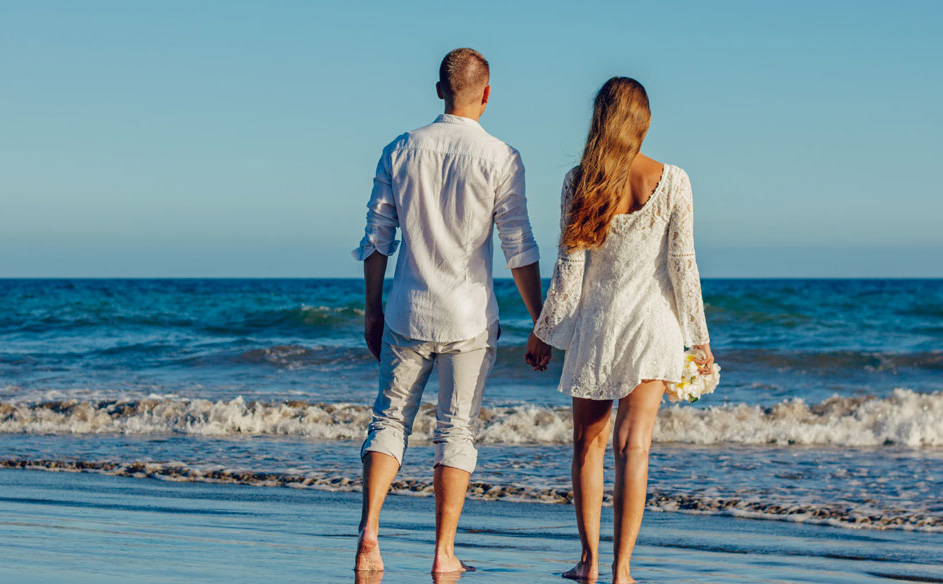牵手在海边散步的新婚夫妇
