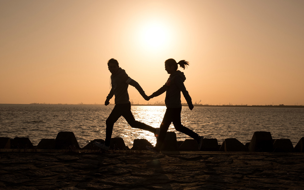夕阳下海边牵手奔跑的浪漫爱情图片