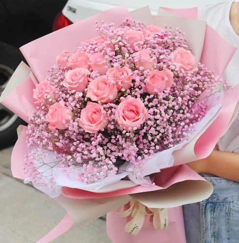 手捧一大束粉红色的玫瑰花